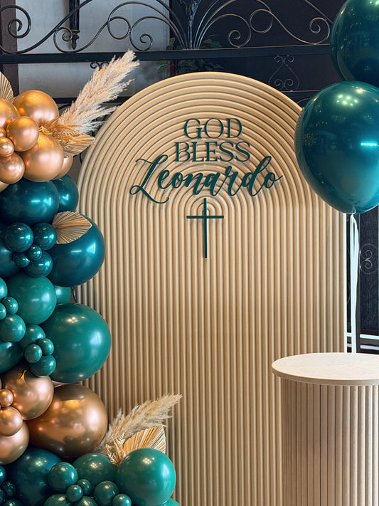 Arched sacrament backdrop with custom name sign and balloon garland available in Toronto at confettimyparty