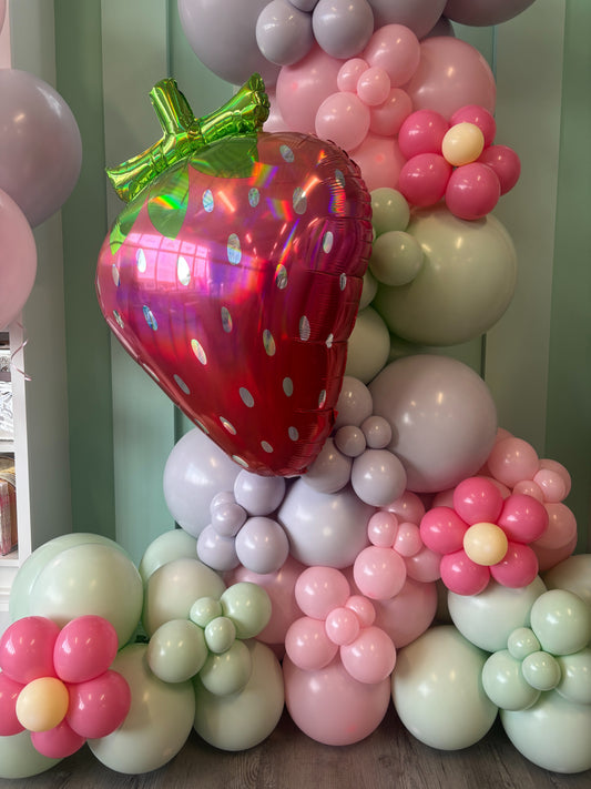 Strawberry themed balloon garland in chalk pink, chalk purple + chalk green and strawberry balloon, styled for a Toronto berry first birthday.