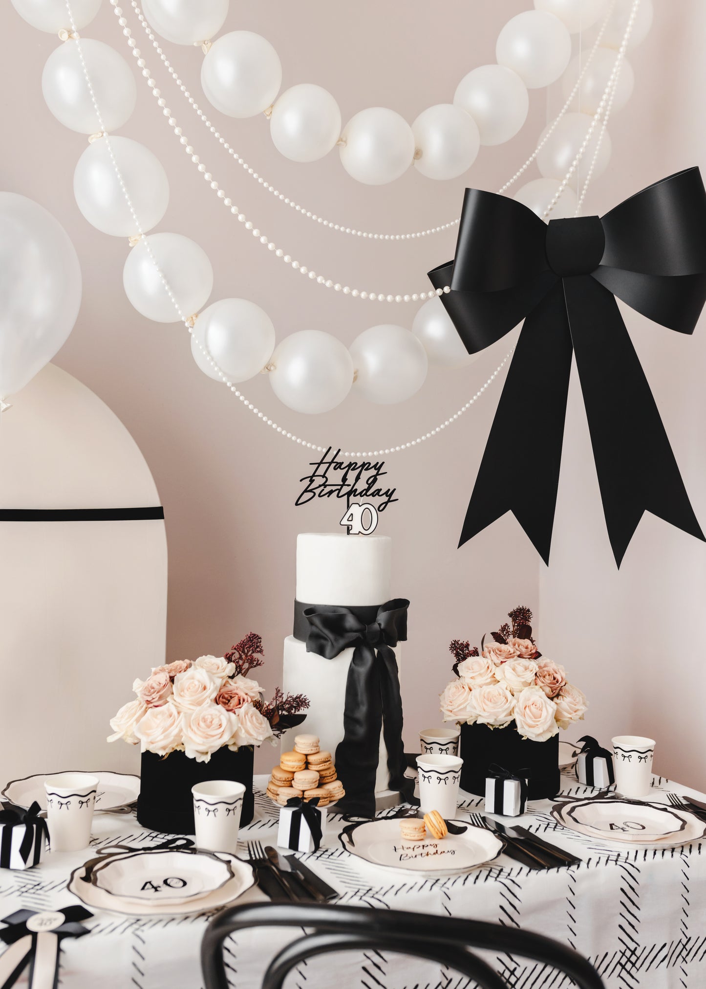 Chic 40th birthday celebration featuring a black and white bow theme and pearl balloon garland.