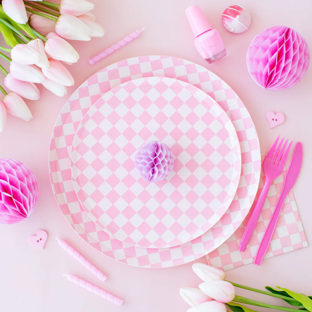 Close-up of pink checkered dessert and dinner plates styled with pink tulips, honeycomb decor, and pastel party accessories.
