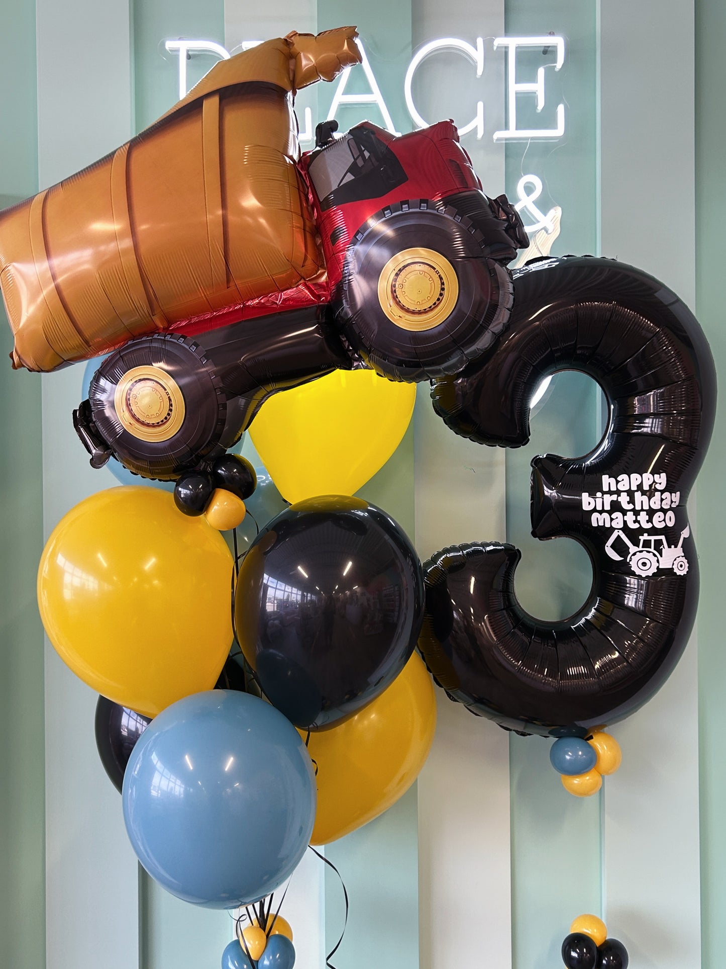 Construction Truck Mini Kid Pop featuring a dump truck foil balloon, jumbo black number balloon, and yellow, black, and blue balloons, available in Toronto