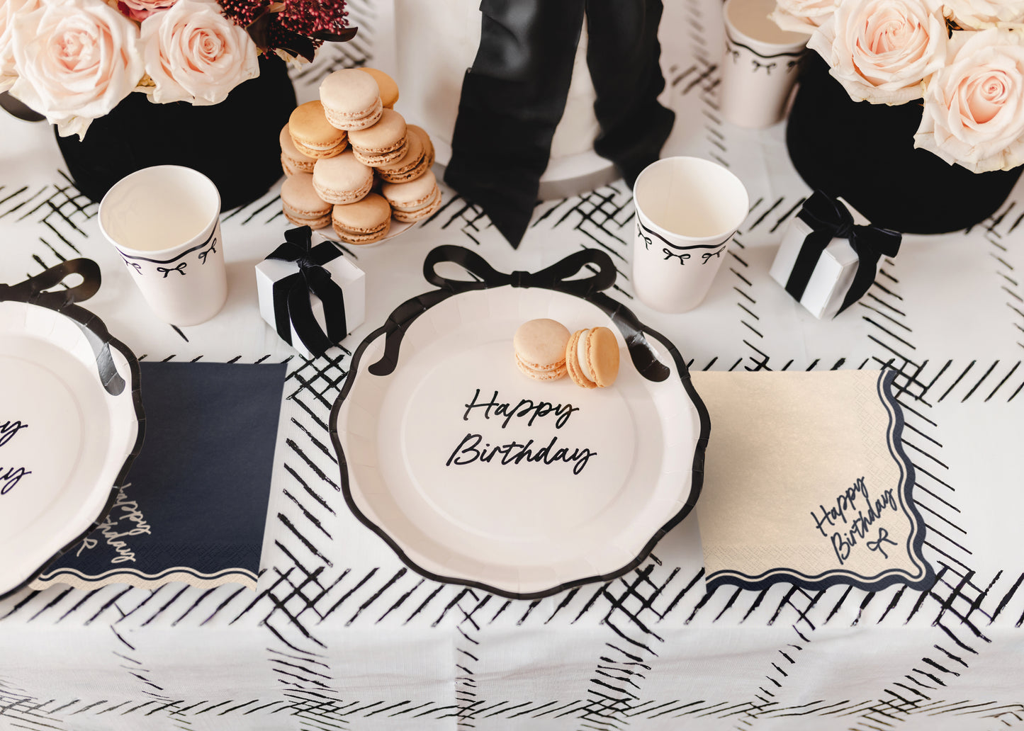Birthday table setup with beige Happy Birthday bow napkins and black and white decor available at our Toronto party shop