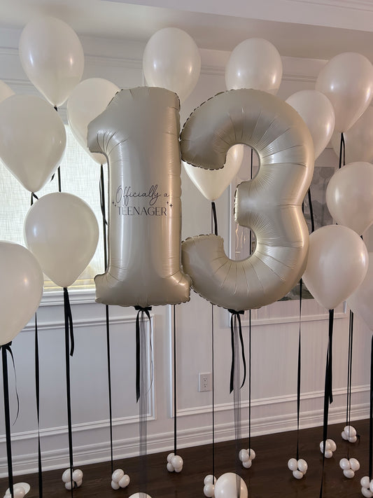 Customizable cream number balloons with black bows, part of a modern birthday balloon setup in Toronto.
