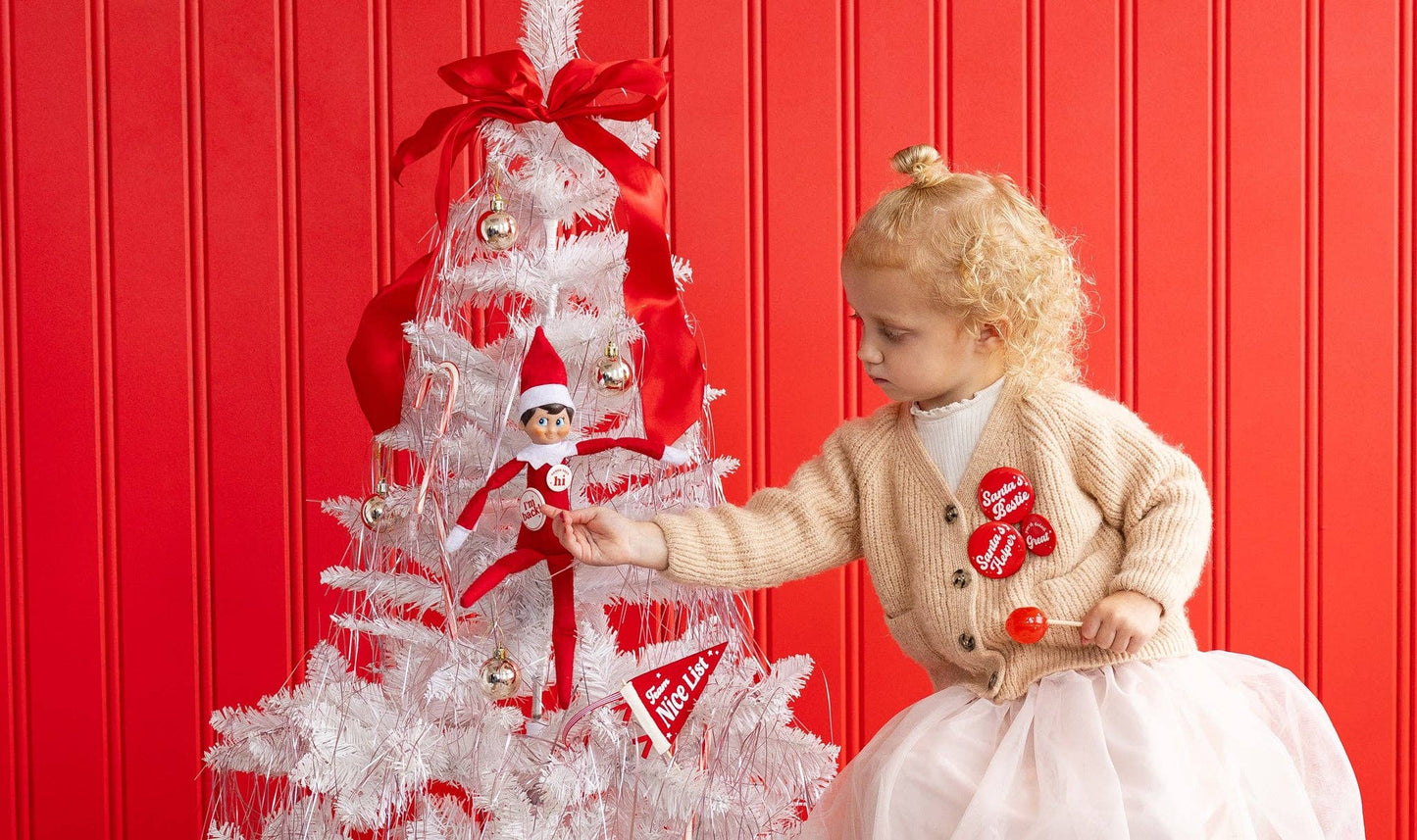 Elf on the Shelf decorated with red “Nice List” pennant and festive buttons in Toronto home.