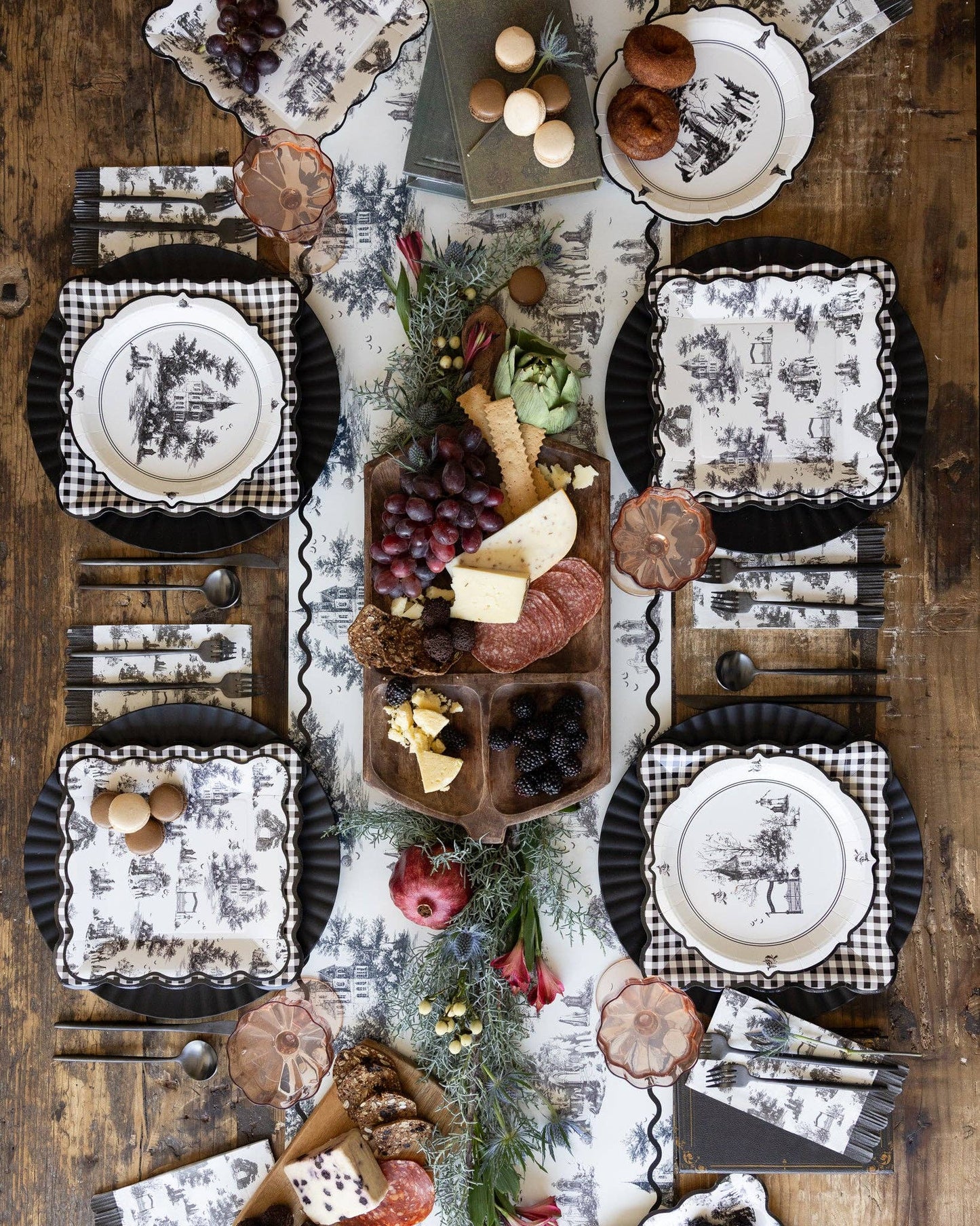 Vintage black and white Halloween party table setting with haunted toile paper plates, napkins and spooky table decor.