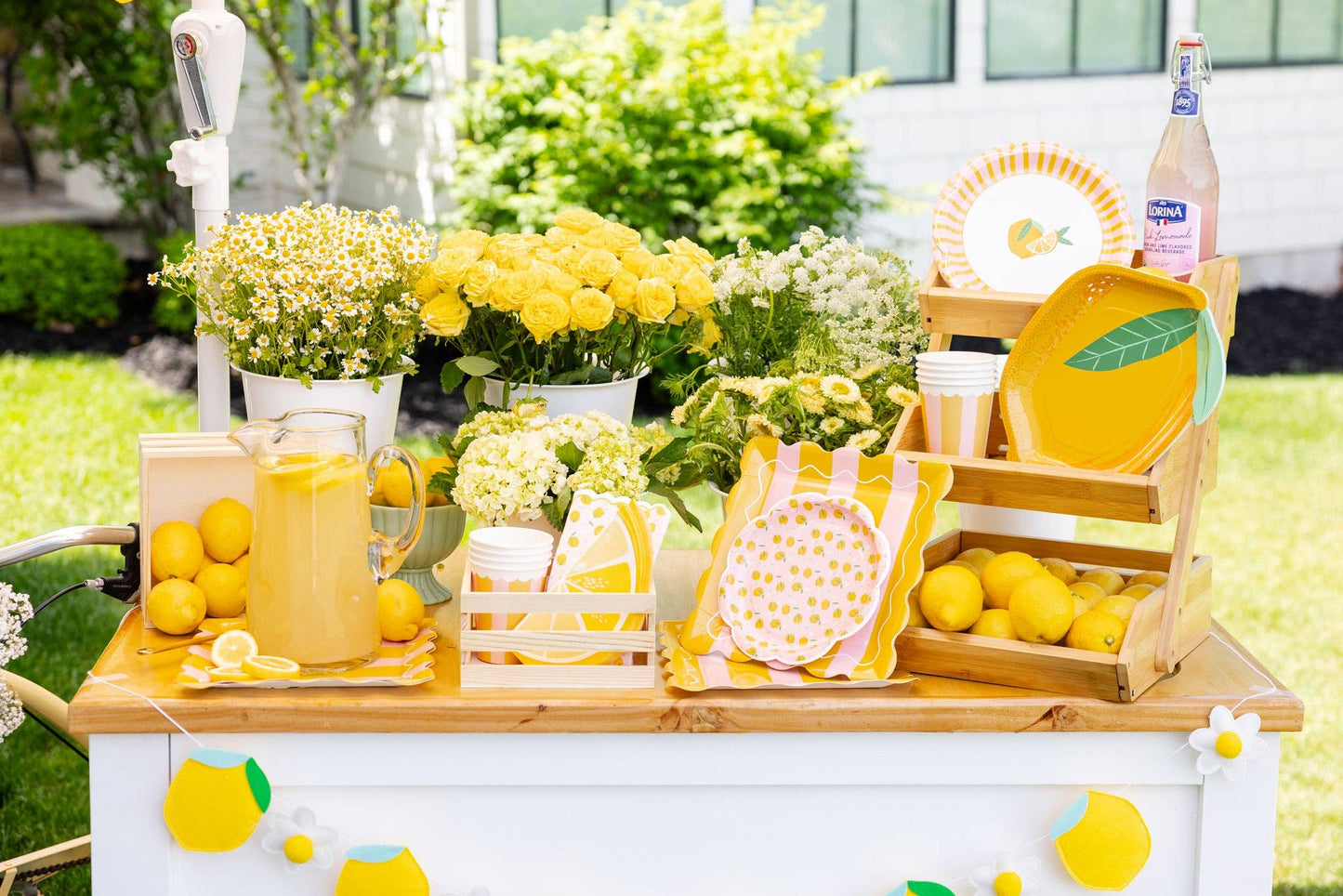 Outdoor picnic table setup with lemon-themed plates and striped square plates for a cheerful summer party.