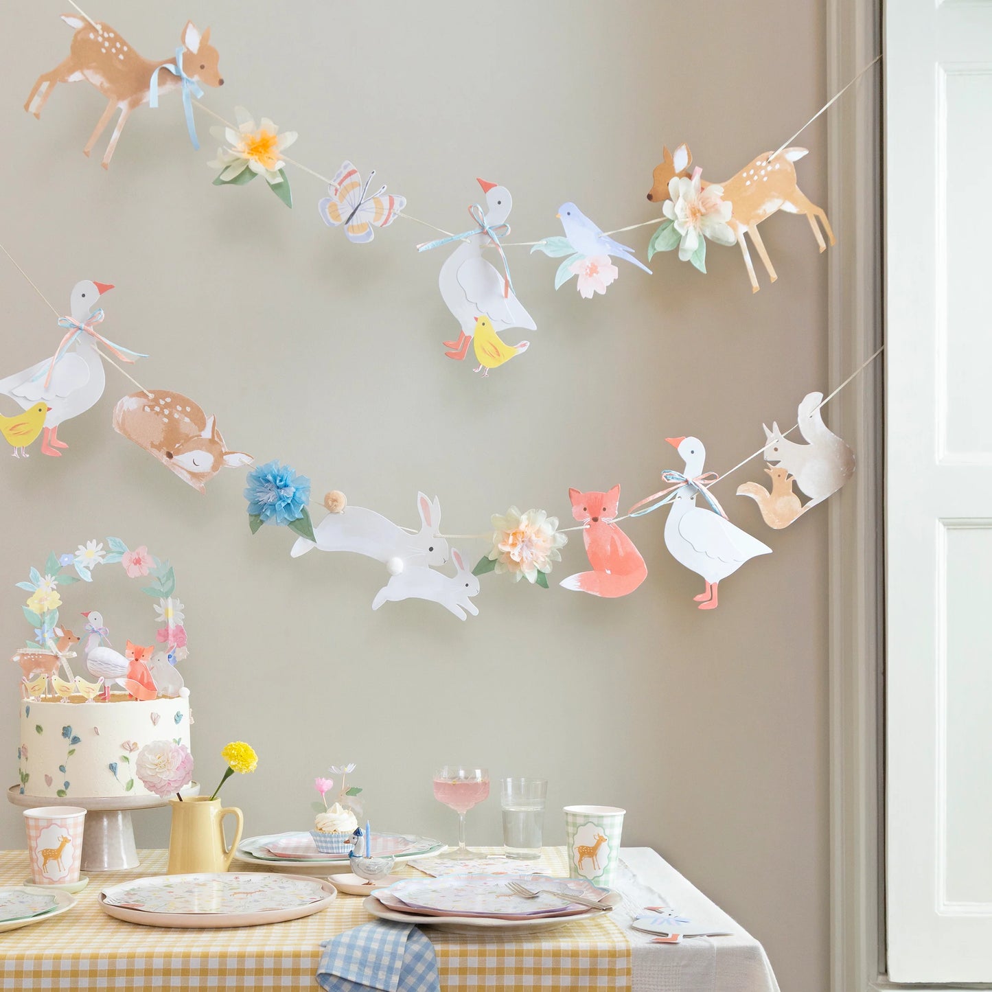Meri Meri Little Animals garland styled above a woodland party table with cake and pastel tableware, available at our Toronto party shop.
