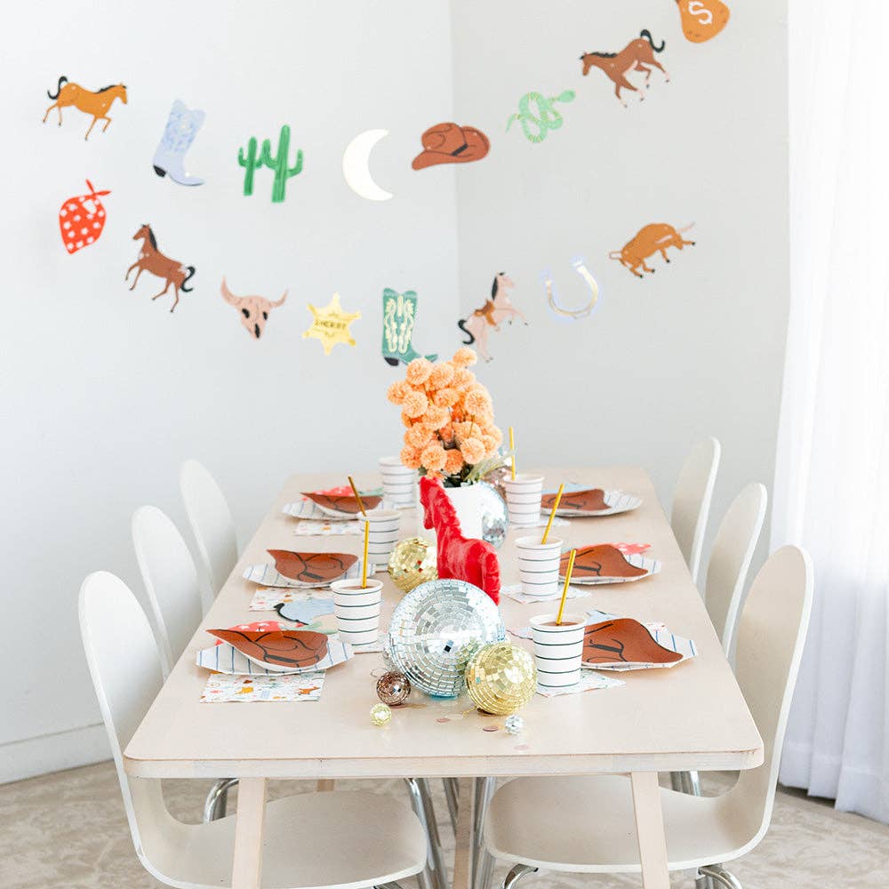 Western-themed kidsβ party table setting with cowboy hat plates, boot napkins, and themed tableware.