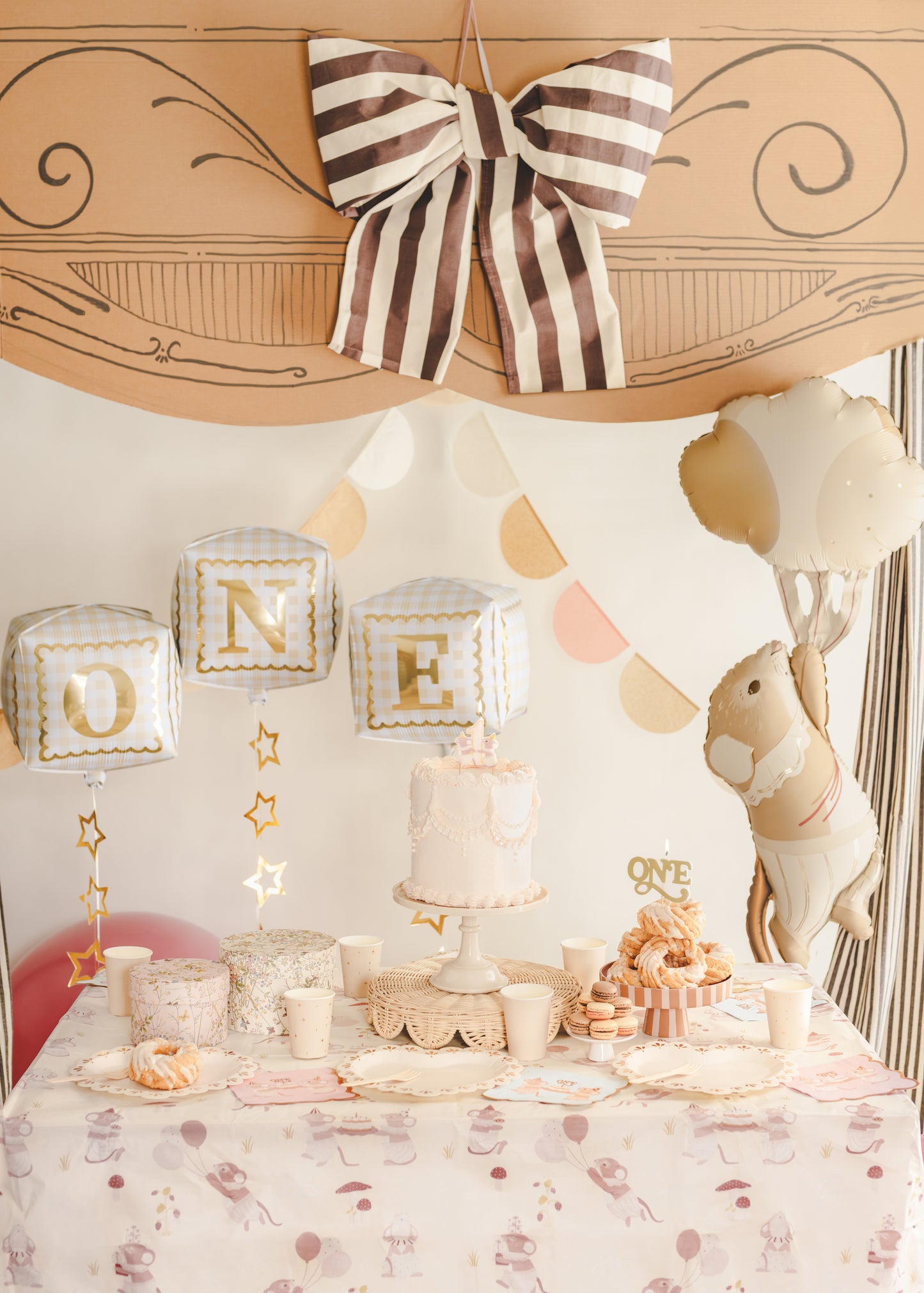 “ONE” cube foil balloons styled above a first birthday cake table with neutral decor, available at our Toronto party shop.