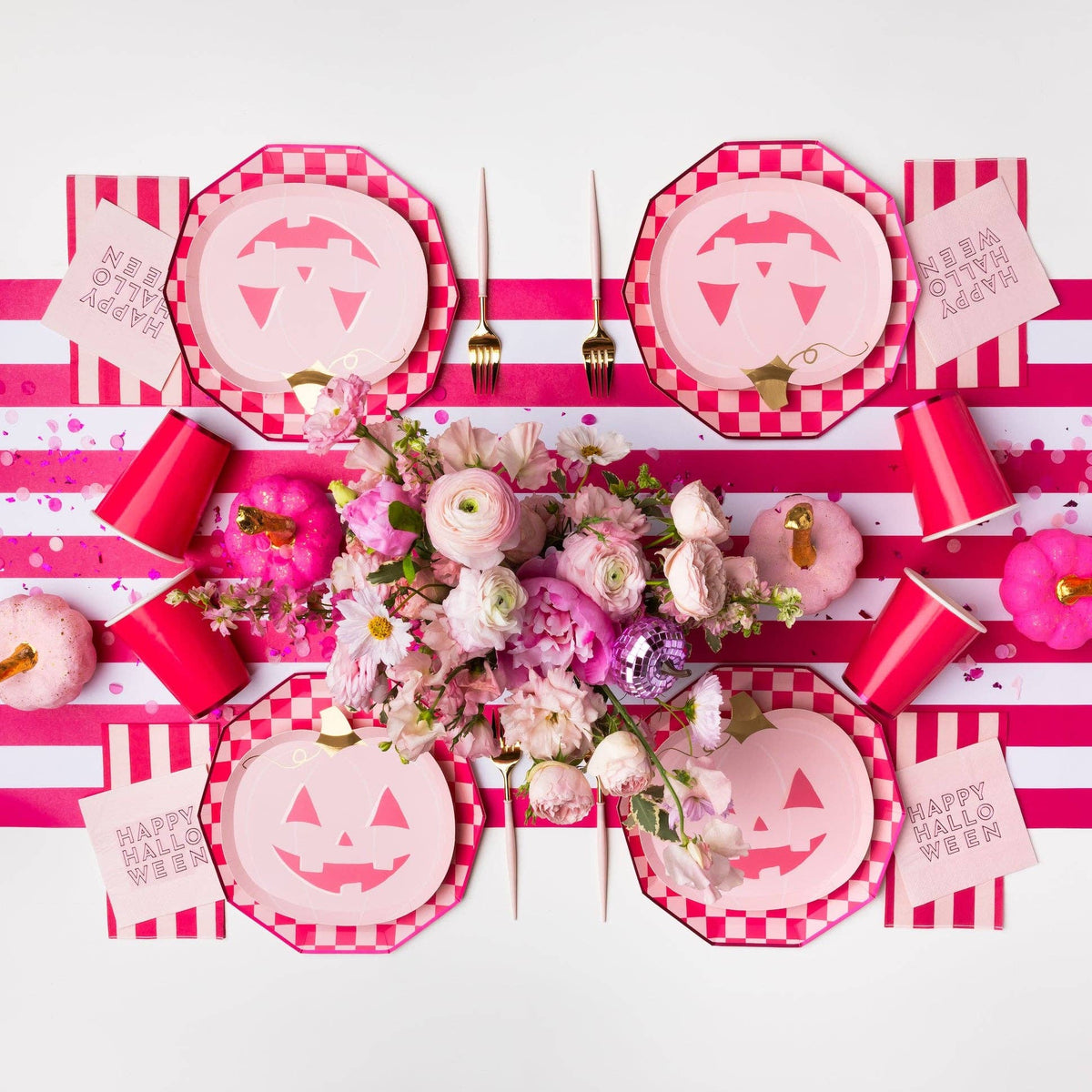 Pink Halloween party table with jack-o'-lantern plates, checkerboard plates and pink party decor