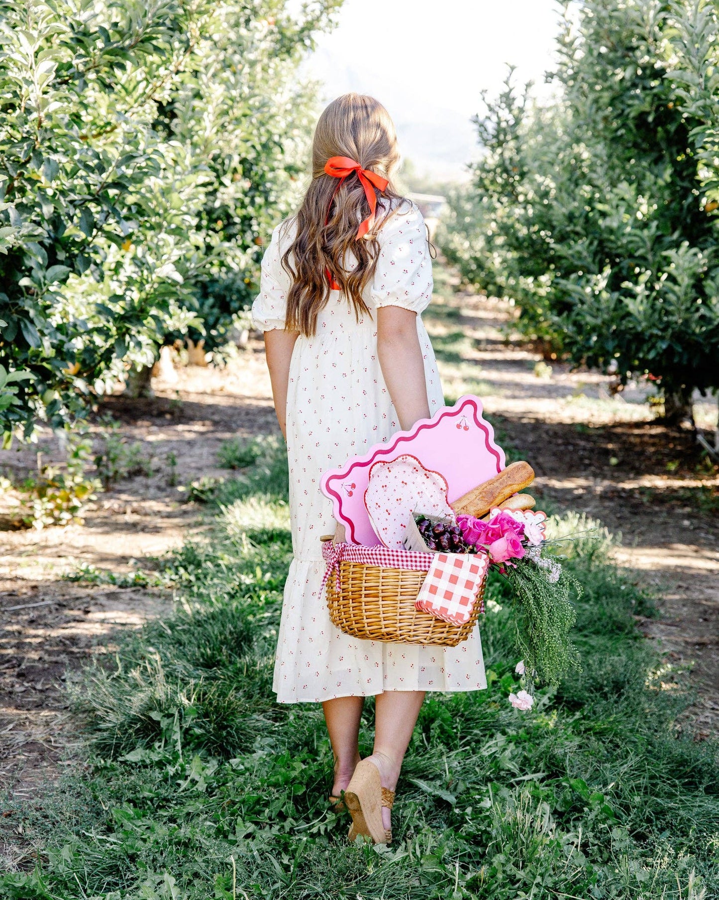 Red gingham dinner napkin shown in a picnic-style setting with cherry-themed details, available at Confetti My Party in Toronto