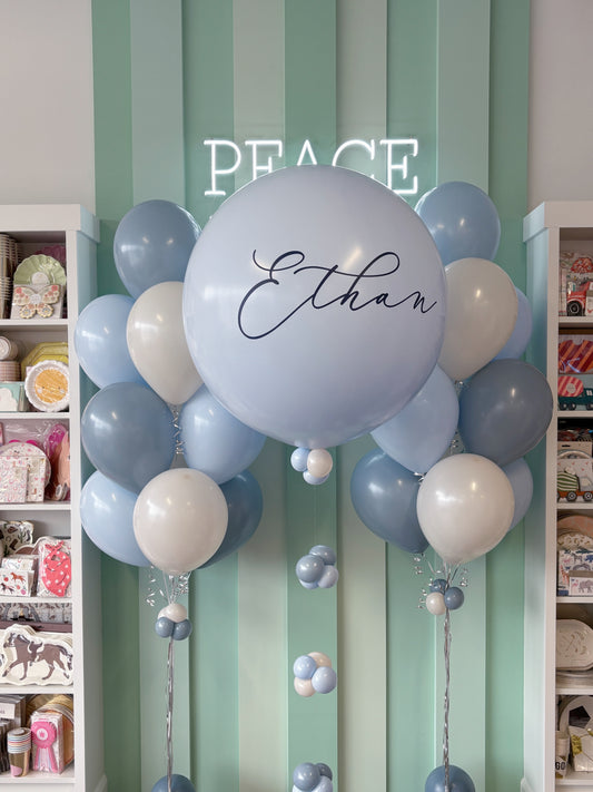Blue jumbo personalized name balloon with coordinating blue and cream helium bouquets for a First Communion or Confirmation celebration in Toronto.
