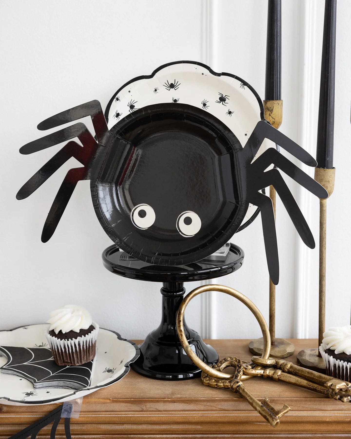 Black cake stand displaying two spider plates and halloween decor.