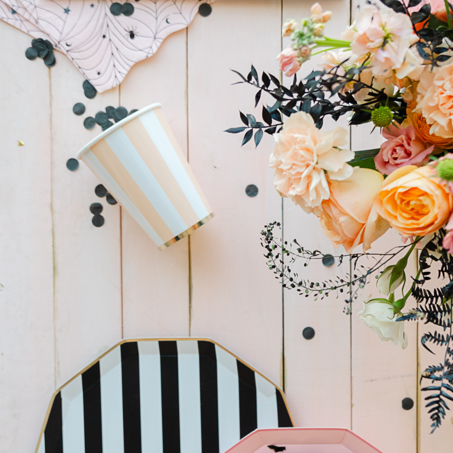 Decorative items including a striped cup, geometric plate, and floral arrangement on a wooden surface.