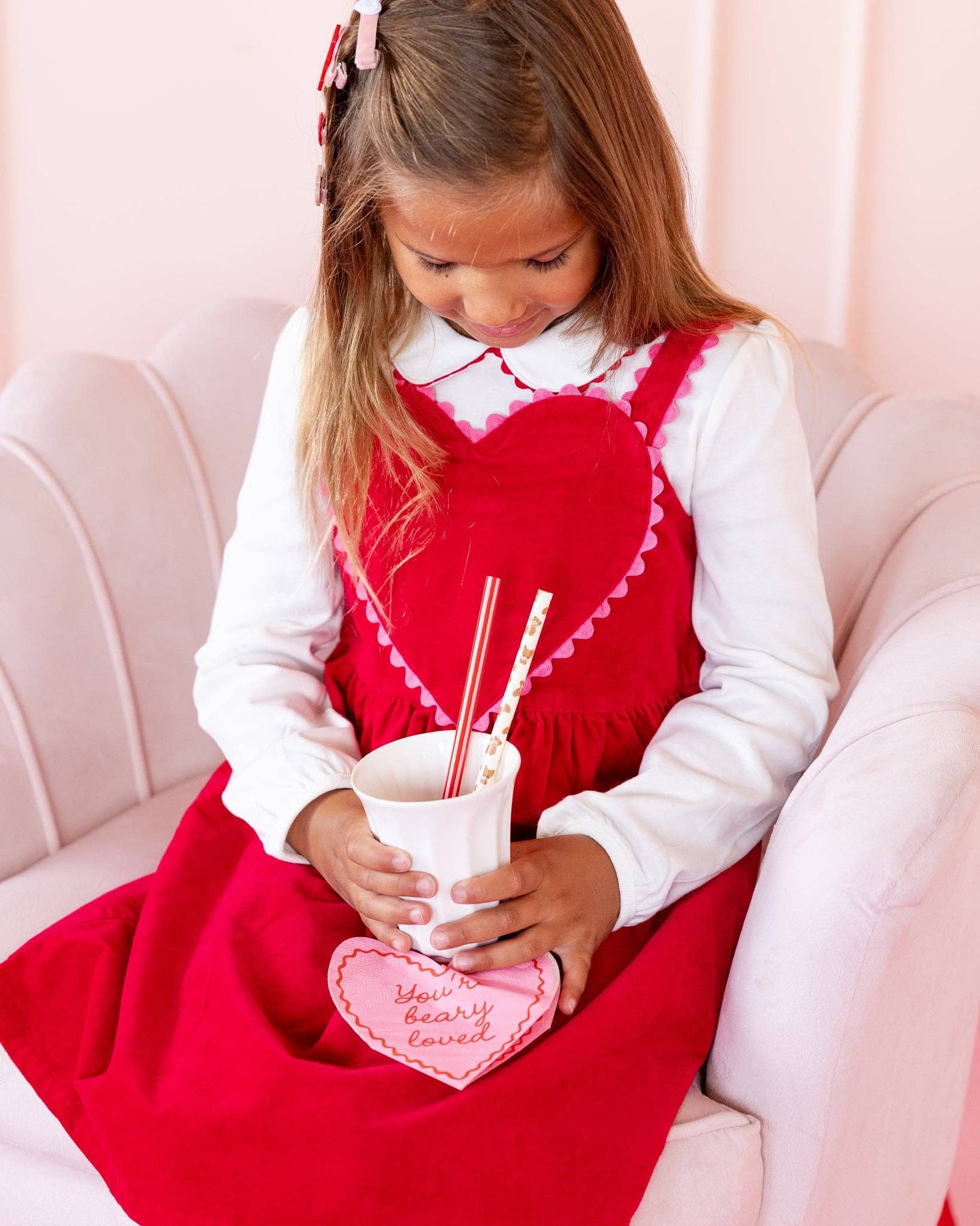 Child holding “You’re Beary Loved” heart shaped napkins styled for a Valentine’s Day celebration