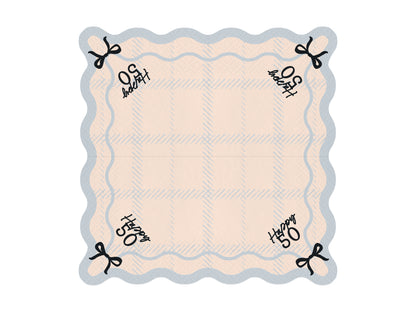 Flat lay of Happy 50 scalloped napkin with pastel plaid pattern and bow detail, ideal for 50th birthday parties.