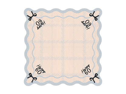 Flat lay of Happy 60 scalloped napkin with pastel plaid pattern and bow detail, ideal for 60th birthday parties.