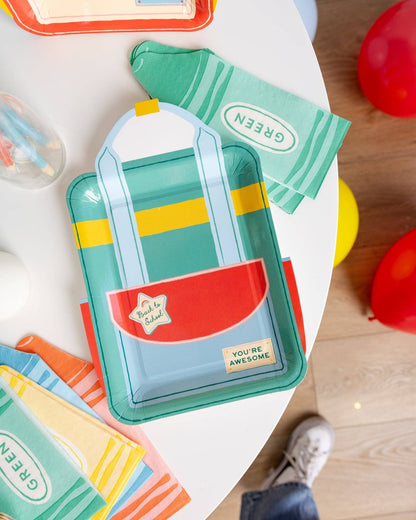 Green backpack shaped paper plate styled with colourful school-themed napkins and decorations available at our Toronto party shop.