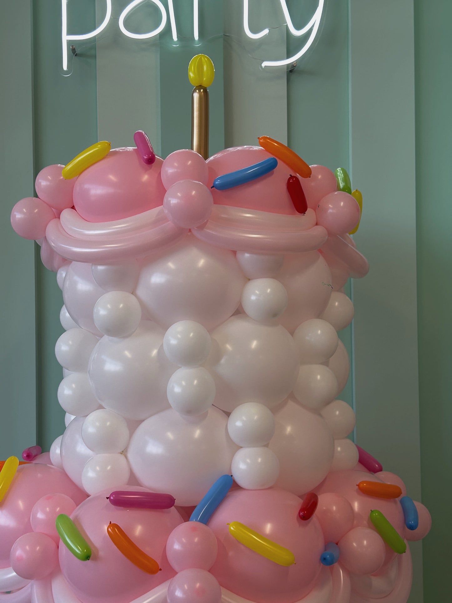 Giant Balloon Birthday Cake close-up showing pastel pink and white balloon layers with colourful sprinkle accents