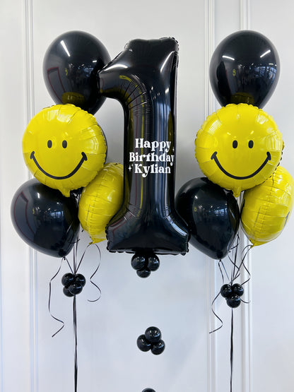 Black + yellow smiley face birthday balloons with personalized jumbo number balloon and helium balloon bouquets in Toronto.