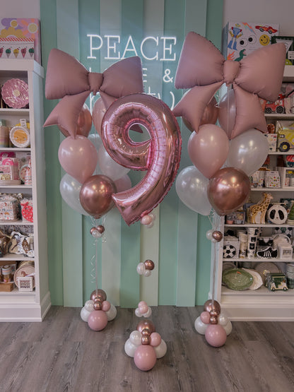 Blush bow balloon bouquets with a rose gold number balloon, styled in soft pink and pearl tones, sold in Toronto at Confetti My Party.