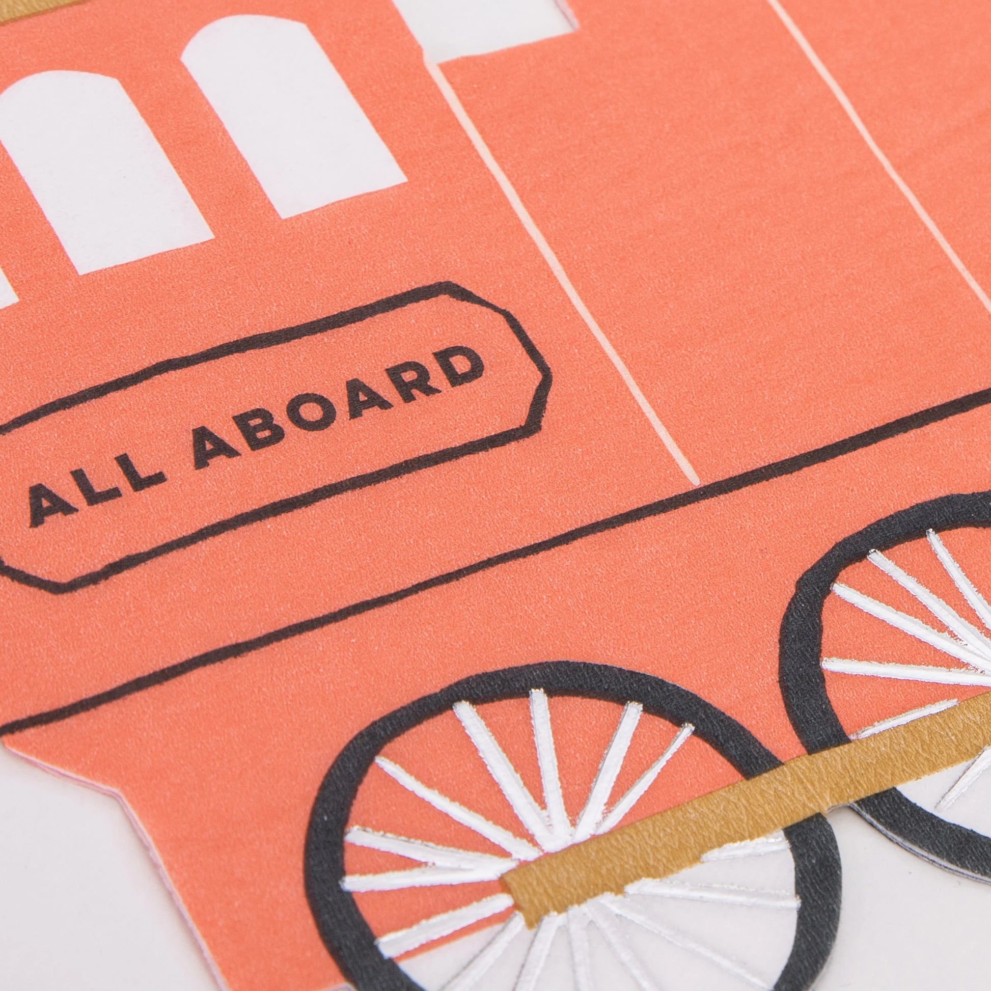 Close-up of red train napkin with detailed wheel design and “All Aboard” text