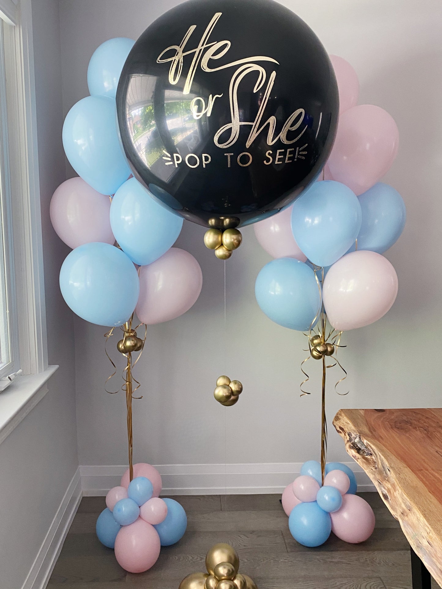 Gender reveal balloon bundle including a jumbo black balloon He or She - POP TO SEE! paired with pink and blue latex balloon bundles.