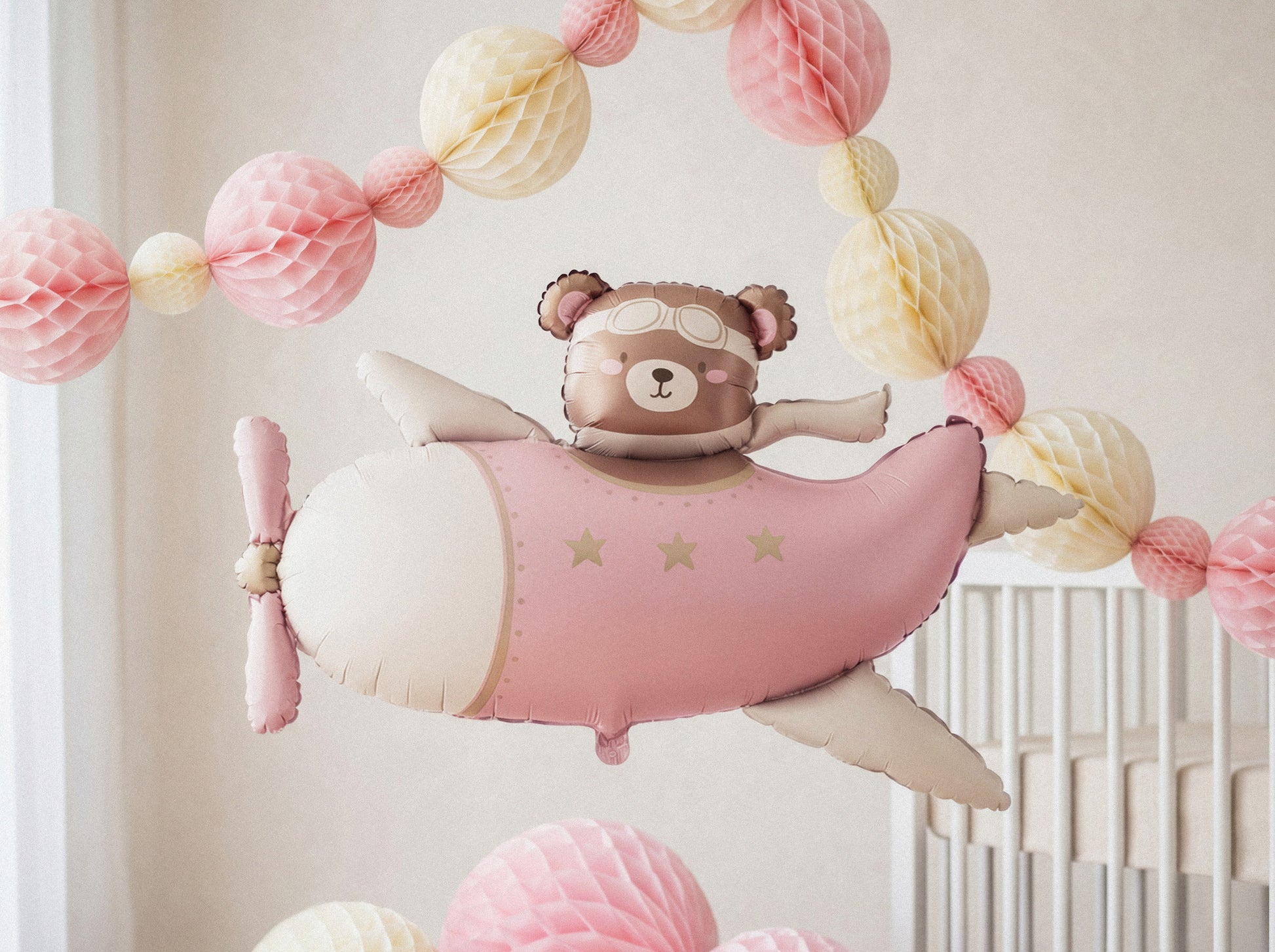 Pink bear airplane foil balloon styled in a pastel baby shower setup with paper decorations, available at our Toronto party shop.