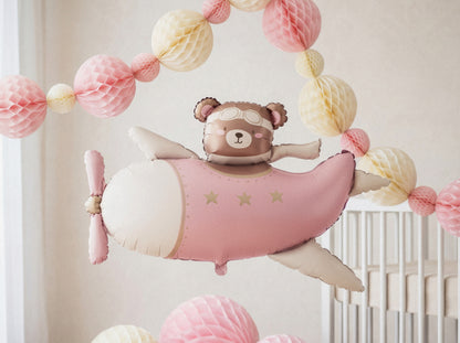 Pink bear airplane foil balloon styled in a pastel baby shower setup with paper decorations, available at our Toronto party shop.