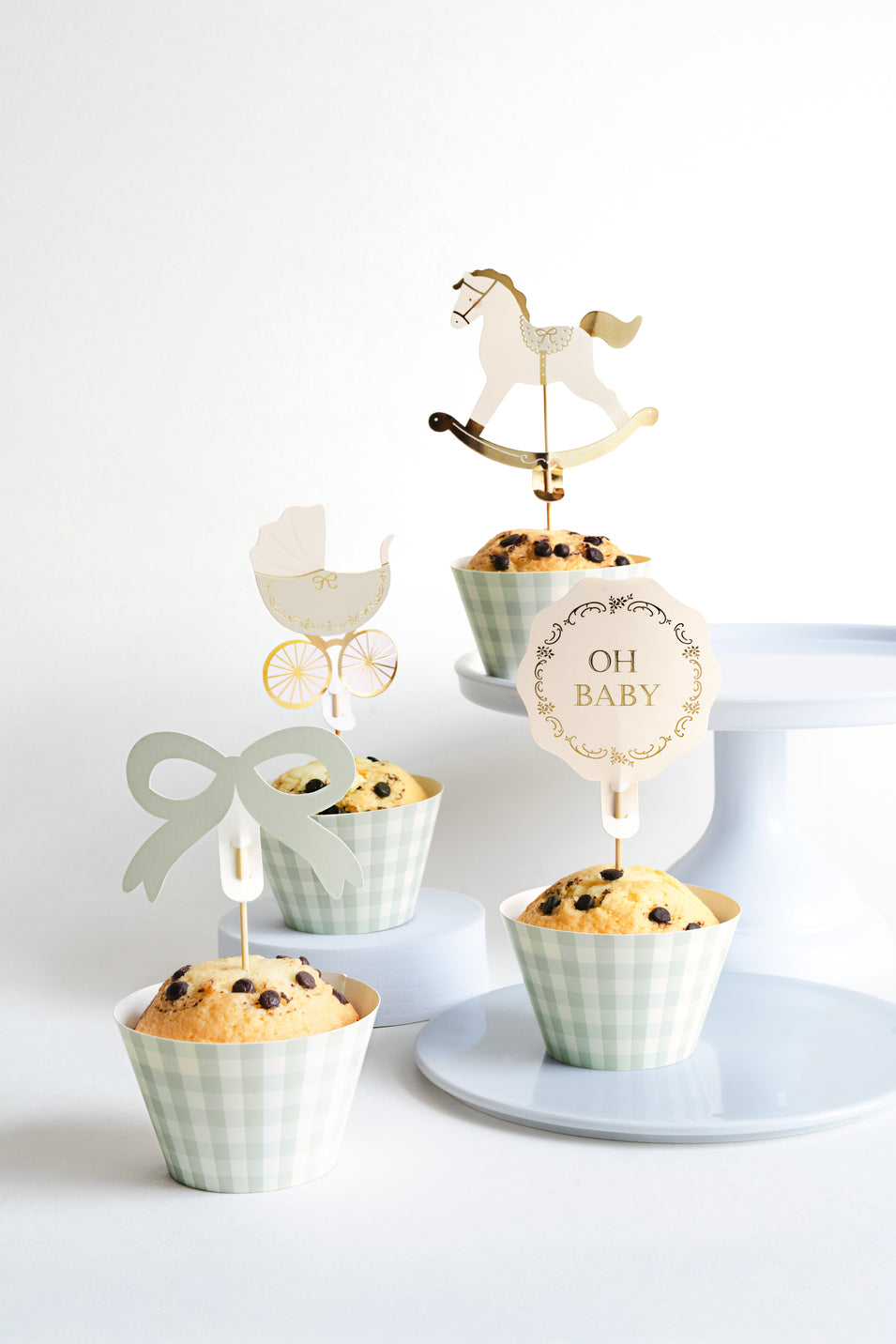 Display of Oh Baby muffins with mint gingham wrappers and gold rocking horse toppers, available in Toronto and shipping across Canada.