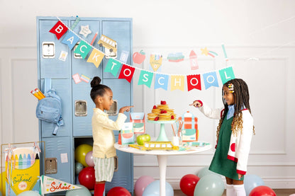 Two children at a 'Back to School' themed party with balloons and decorations.