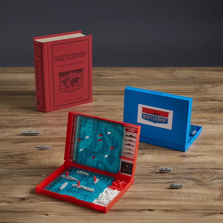 Battleship board game set with red and blue boards on a wooden table.