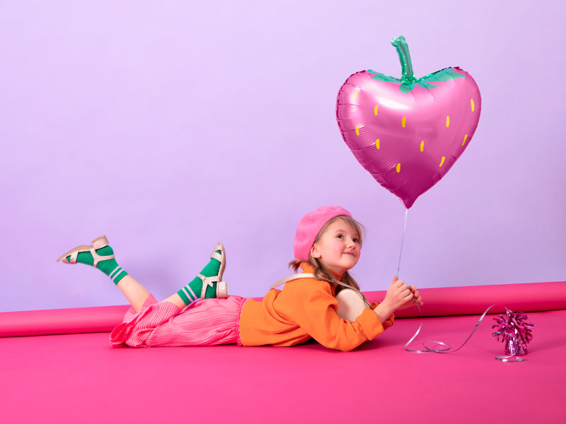 child holding strawberry foil balloon filled with helium
