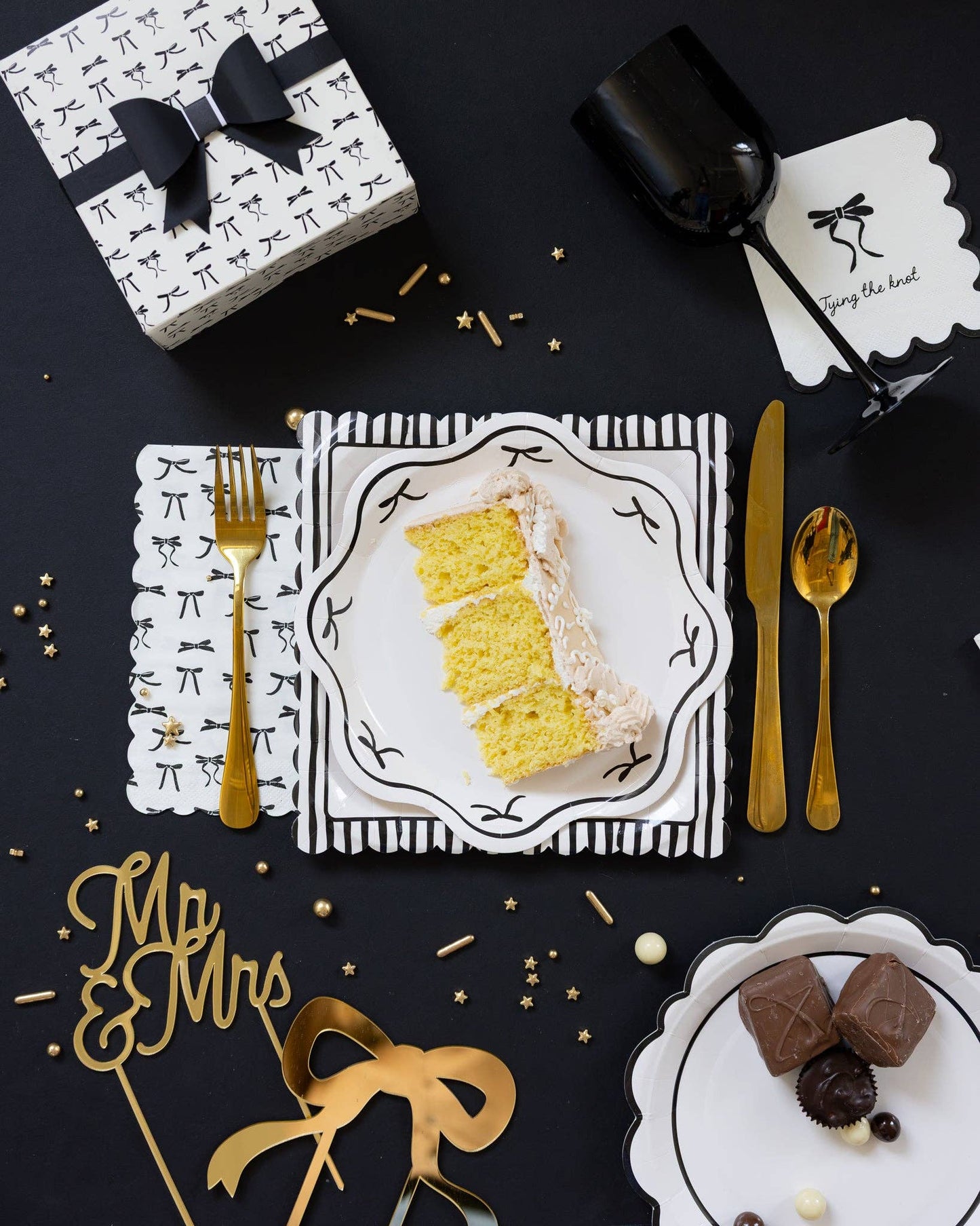 Toronto bridal table setup with black scalloped plates, bow-patterned napkins, and gold cutlery in a chic black-and-white theme.