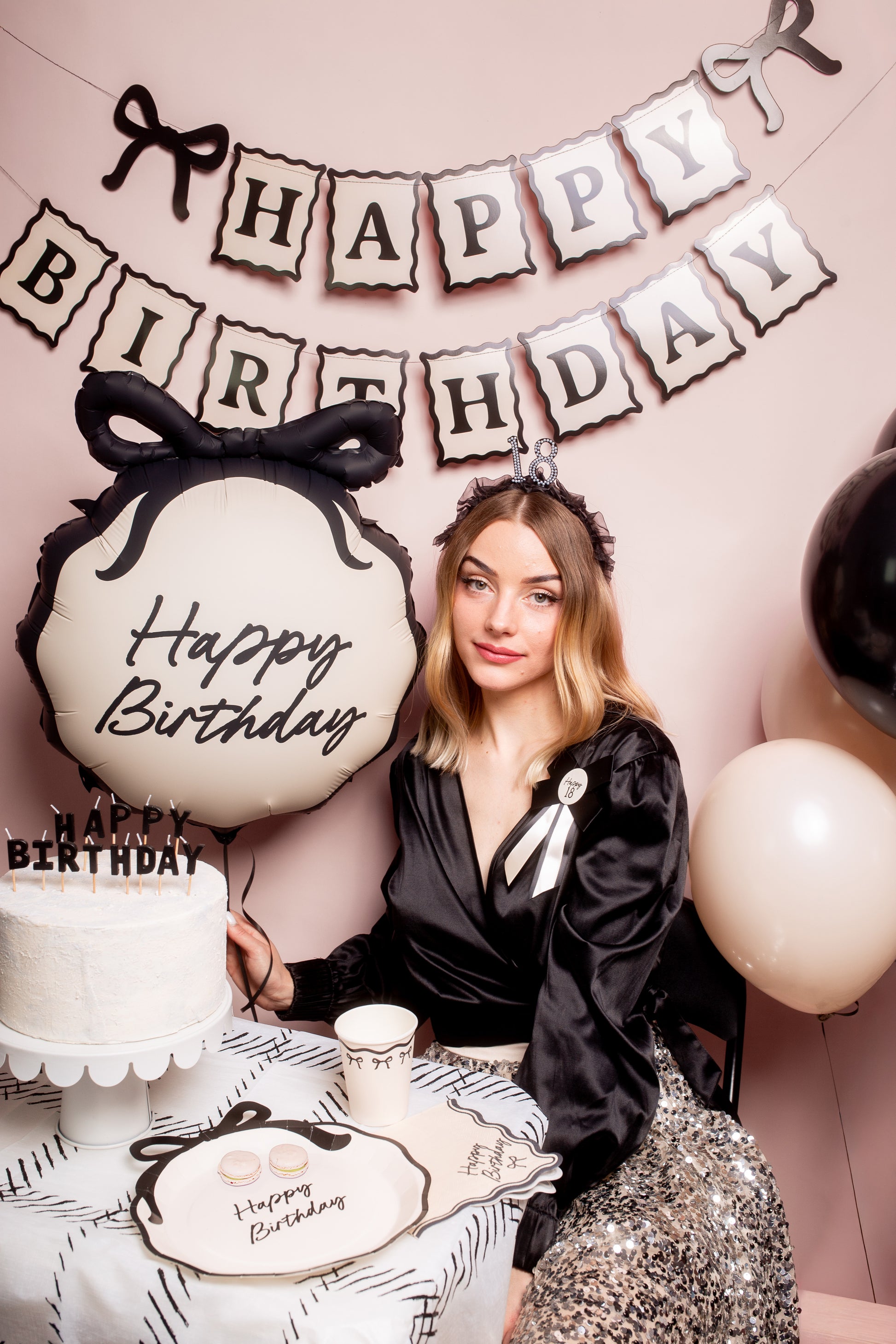 Black bow themed birthday setup with Happy Birthday foil balloon, banner, and cake styling, available at our Toronto party shop.