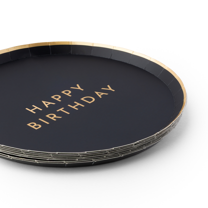 Close-up of black birthday plates with Happy Birthday gold foil lettering and gold trim