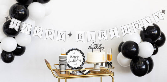 Black Happy Birthday banner styled above a birthday table with black and white balloons available in Toronto and shipping across Canada.