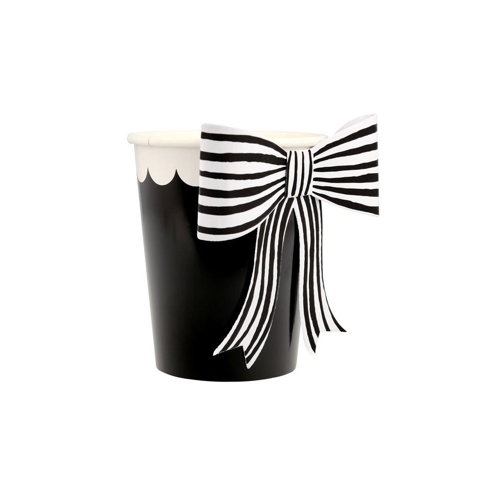 Front view of black paper cup with white scalloped design and black and white striped bow accent