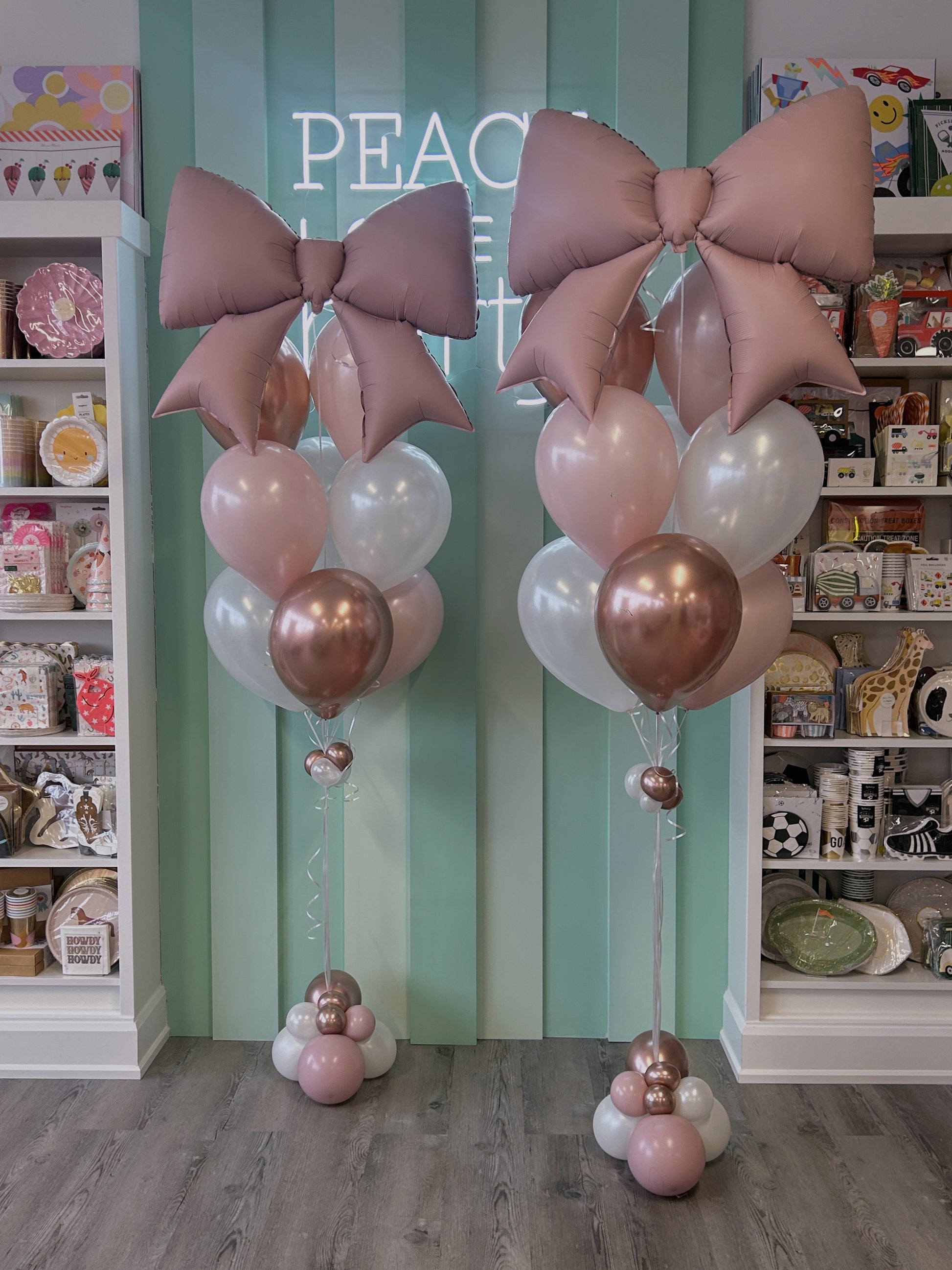 Oversized blush bow balloons paired with pearl white and rose gold balloons, part of a birthday set from Confetti My Party in Toronto.