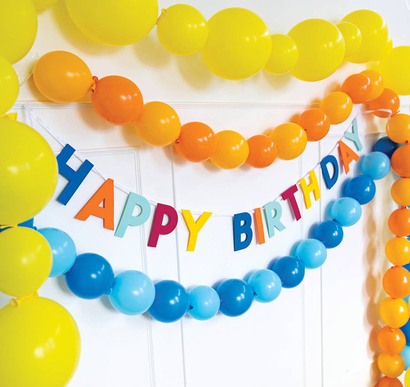Colourful happy birthday banner styled with balloon garland in bright tones, available in Toronto and shipping across Canada