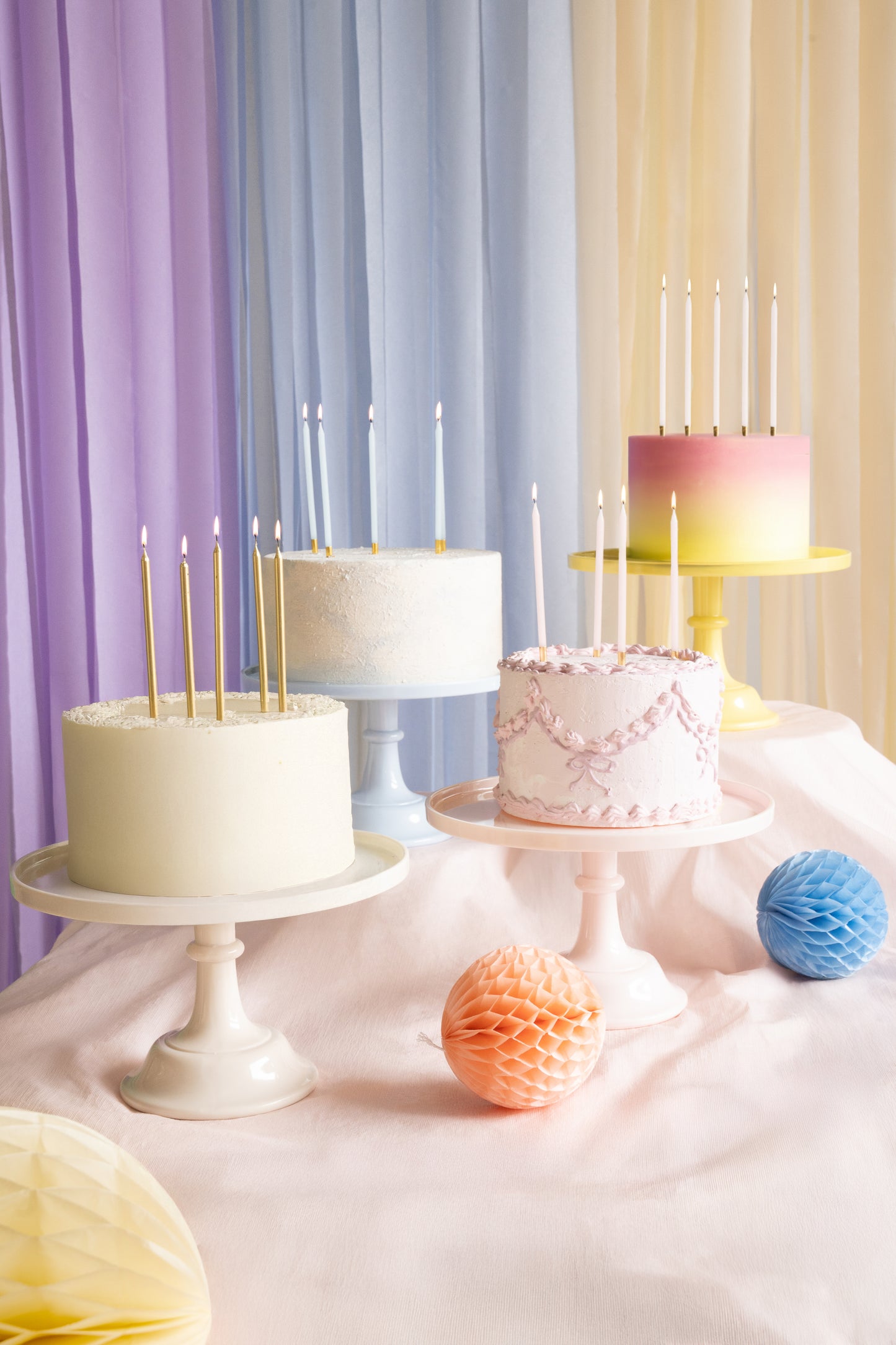 Dessert table with yellow, blue, pink and nude cake stands and pastel cakes on display, available in Toronto and ships across Canada.