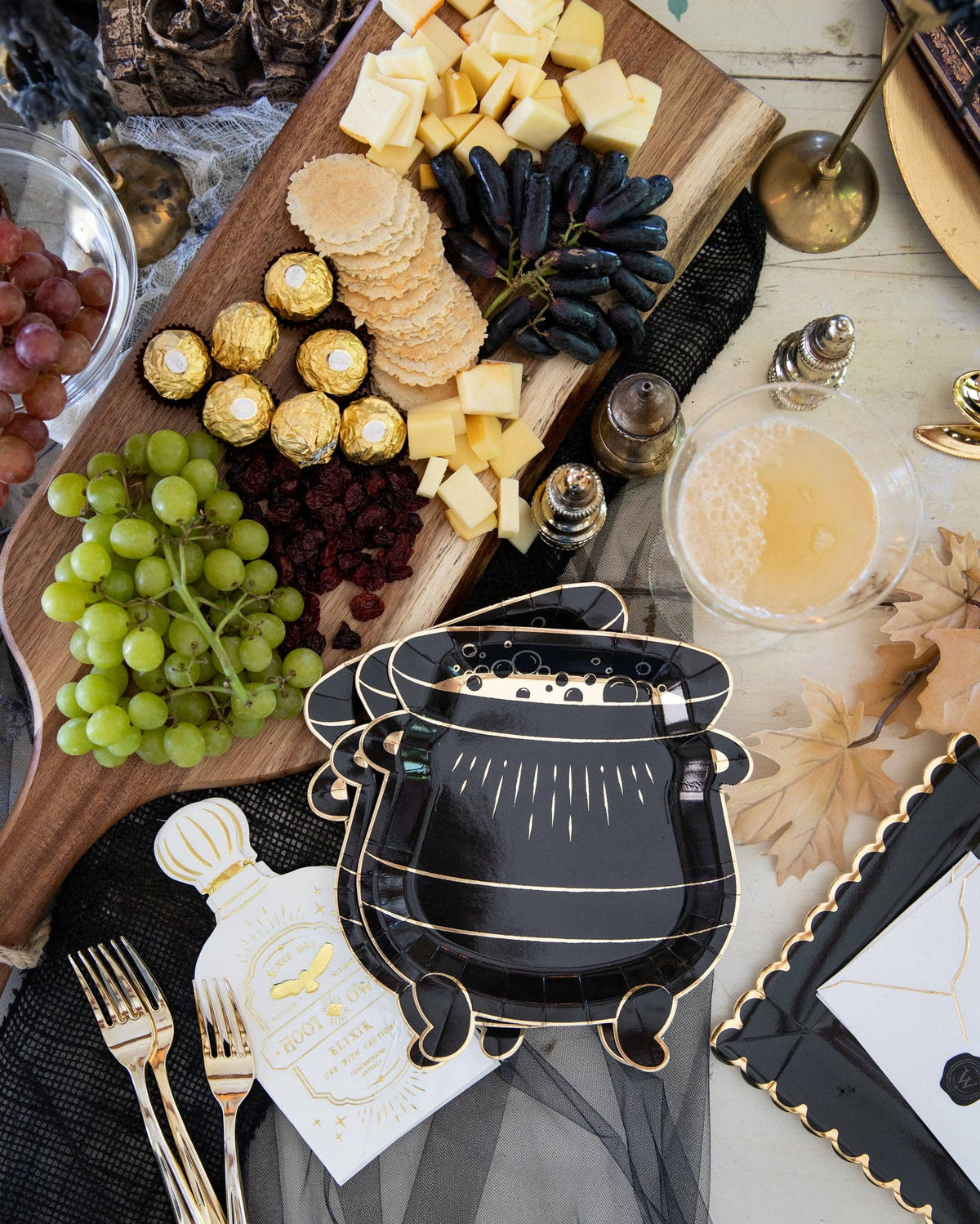 Cauldron shaped paper plates styled on a black and gold Halloween party table