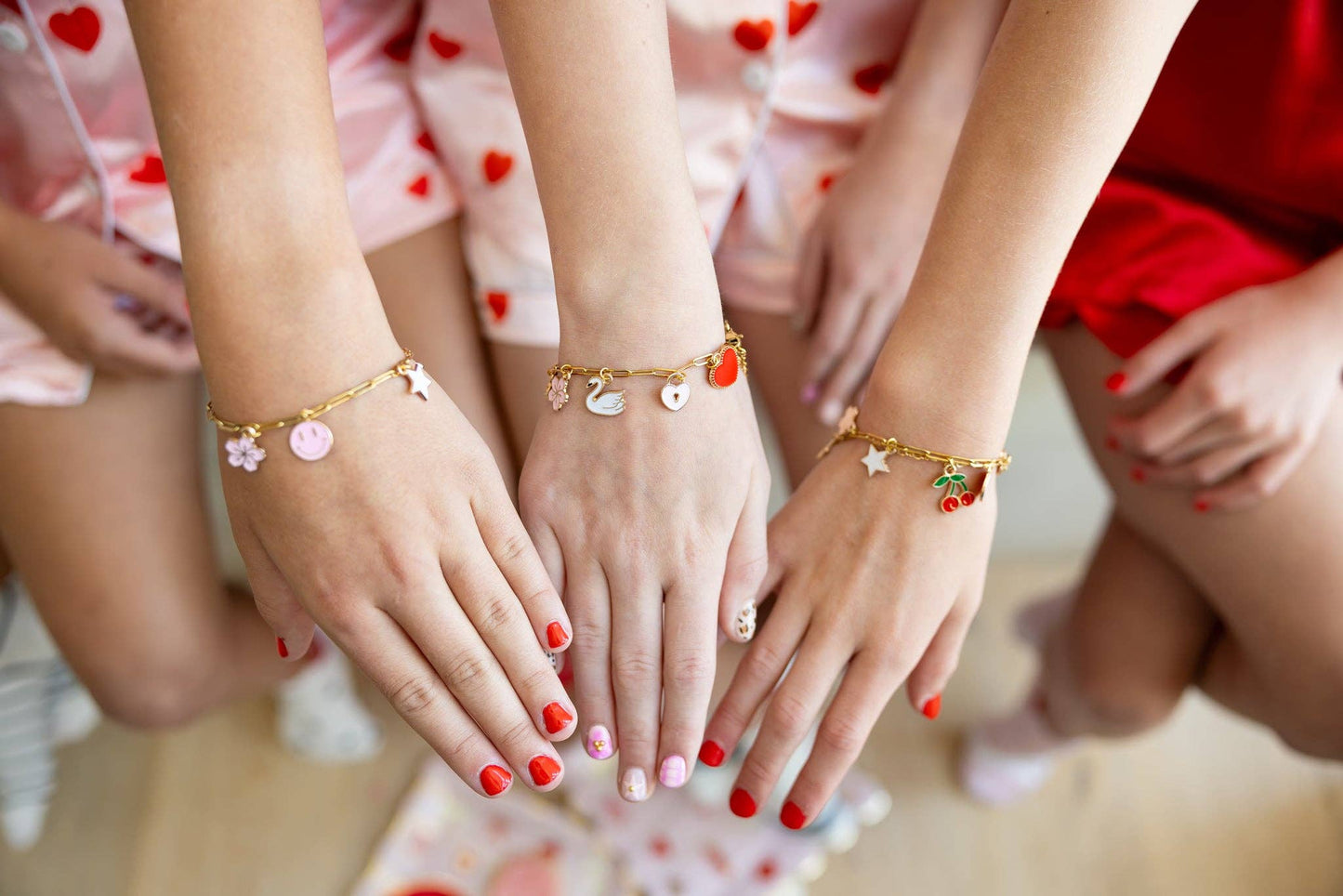 Multiple charm bracelets worn on wrists, each styled with different charms