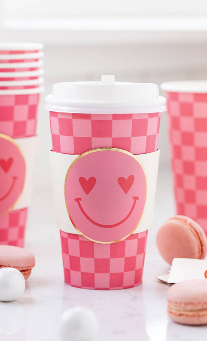 Pink checkered to-go cup with smiley face design on a white background