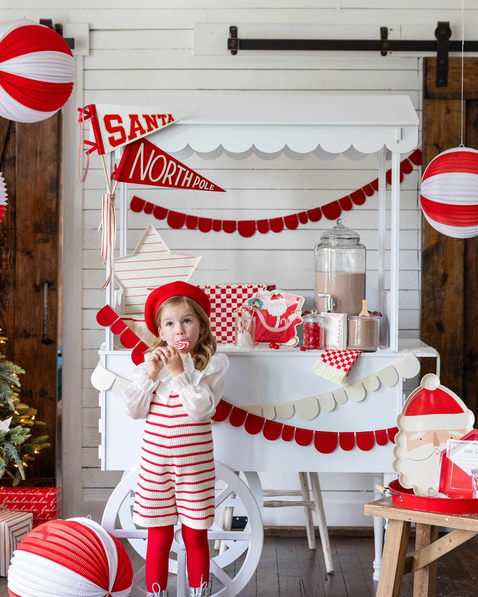 Christmas red and white scalloped banner hanging on a candy cart with festive holiday decorations.