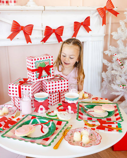 Little girl at festive holiday table with red bow banner and checkered gift boxes, Toronto Christmas décor.