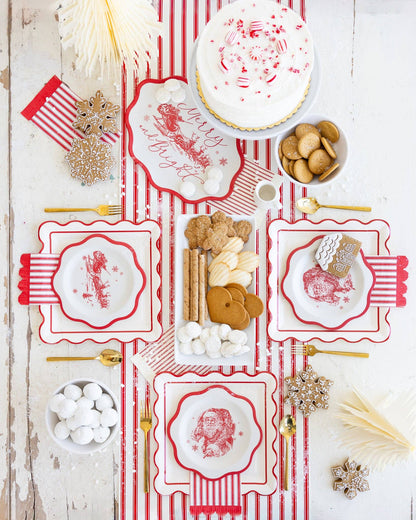 Decorative table setting with red and white patterned plates, cookies, and Christmas decorations on a wooden surface.