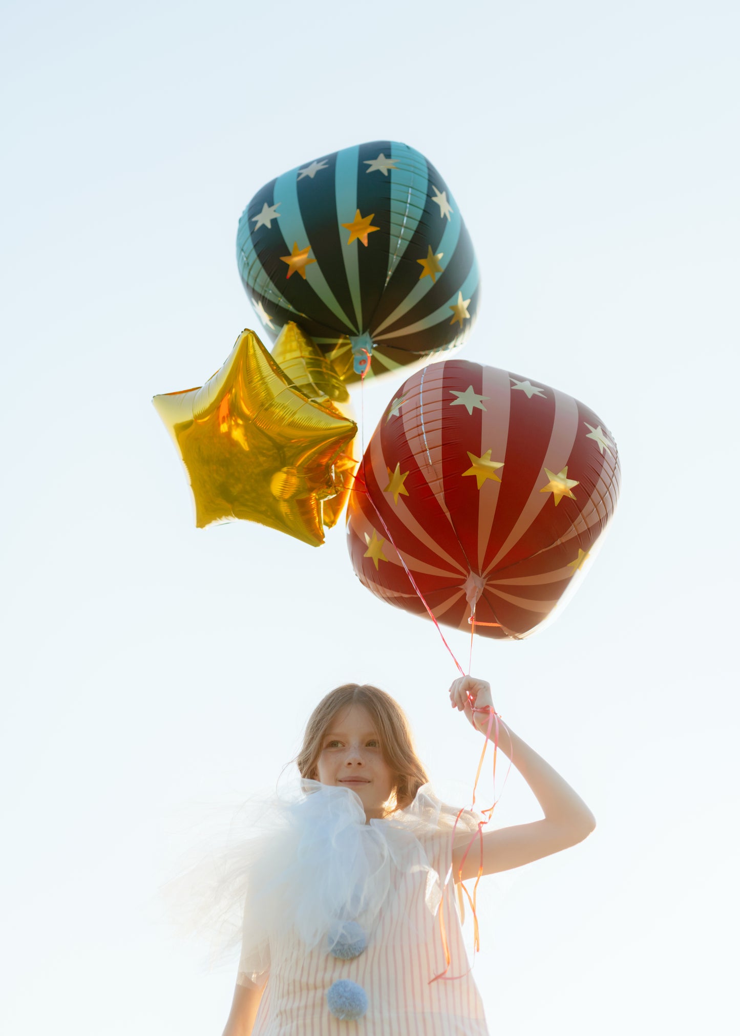 girl holding circus themed helium balloons 