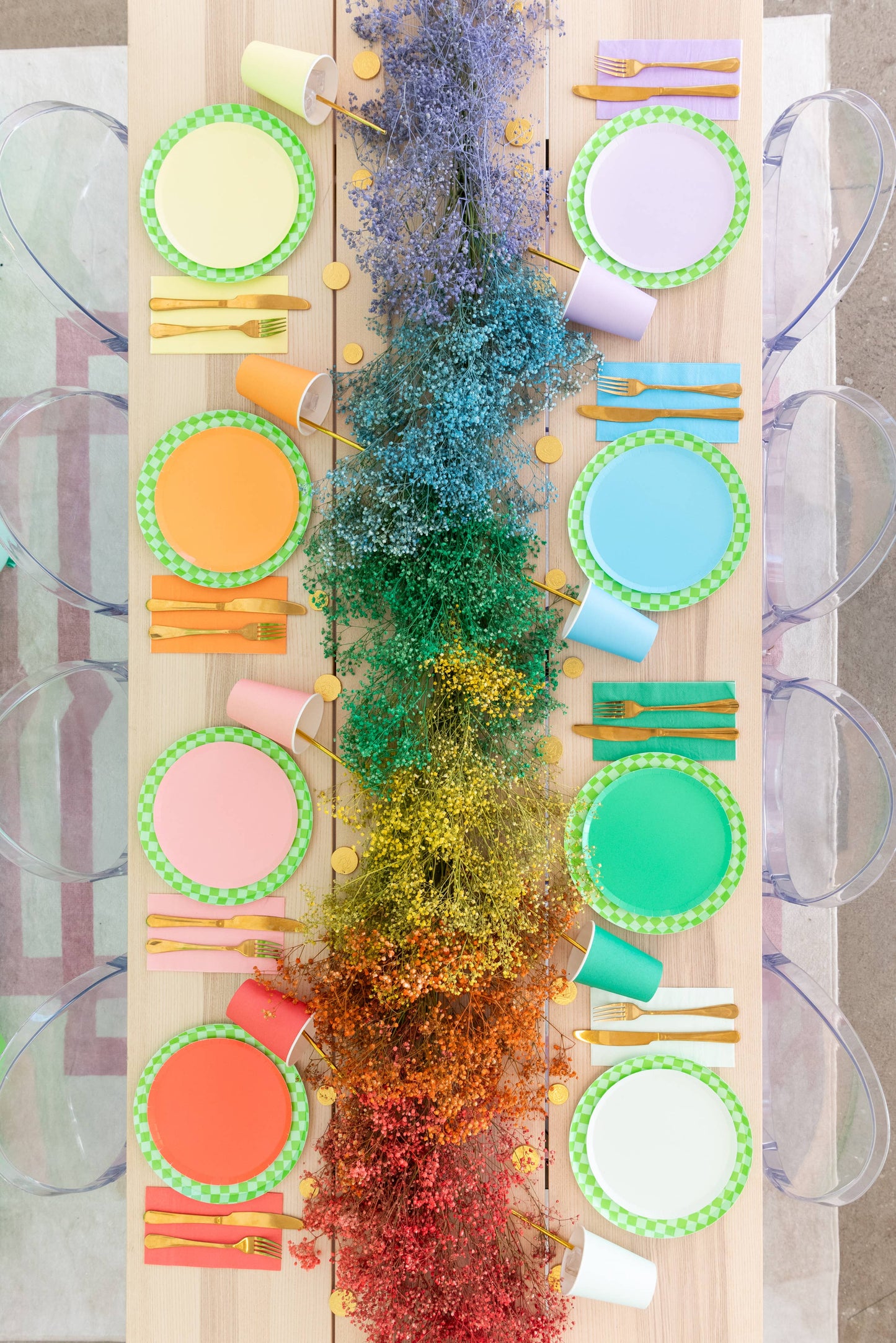 Colorful table setting with plates, cups, and cutlery on a wooden board.