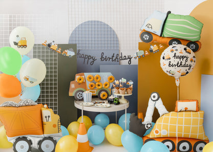 Birthday party setup with construction-themed decorations, balloons, and a 'happy birthday' sign.
